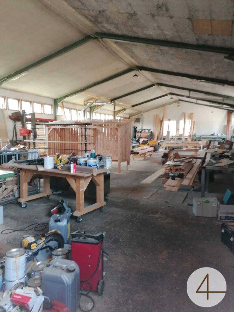 Weitläufige Werkstatt mit hoher Decke, vielen Fenstern und verschiedenen Werkbänken und Materialien.