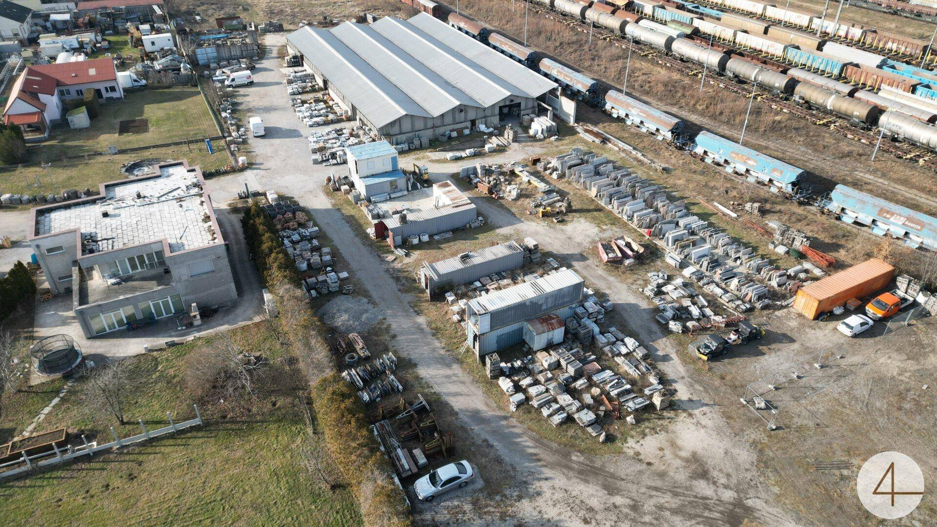 Luftaufnahme eines Gewerbegebiets mit verschiedenen Gebäuden, Lagerflächen und Bahngleisen.