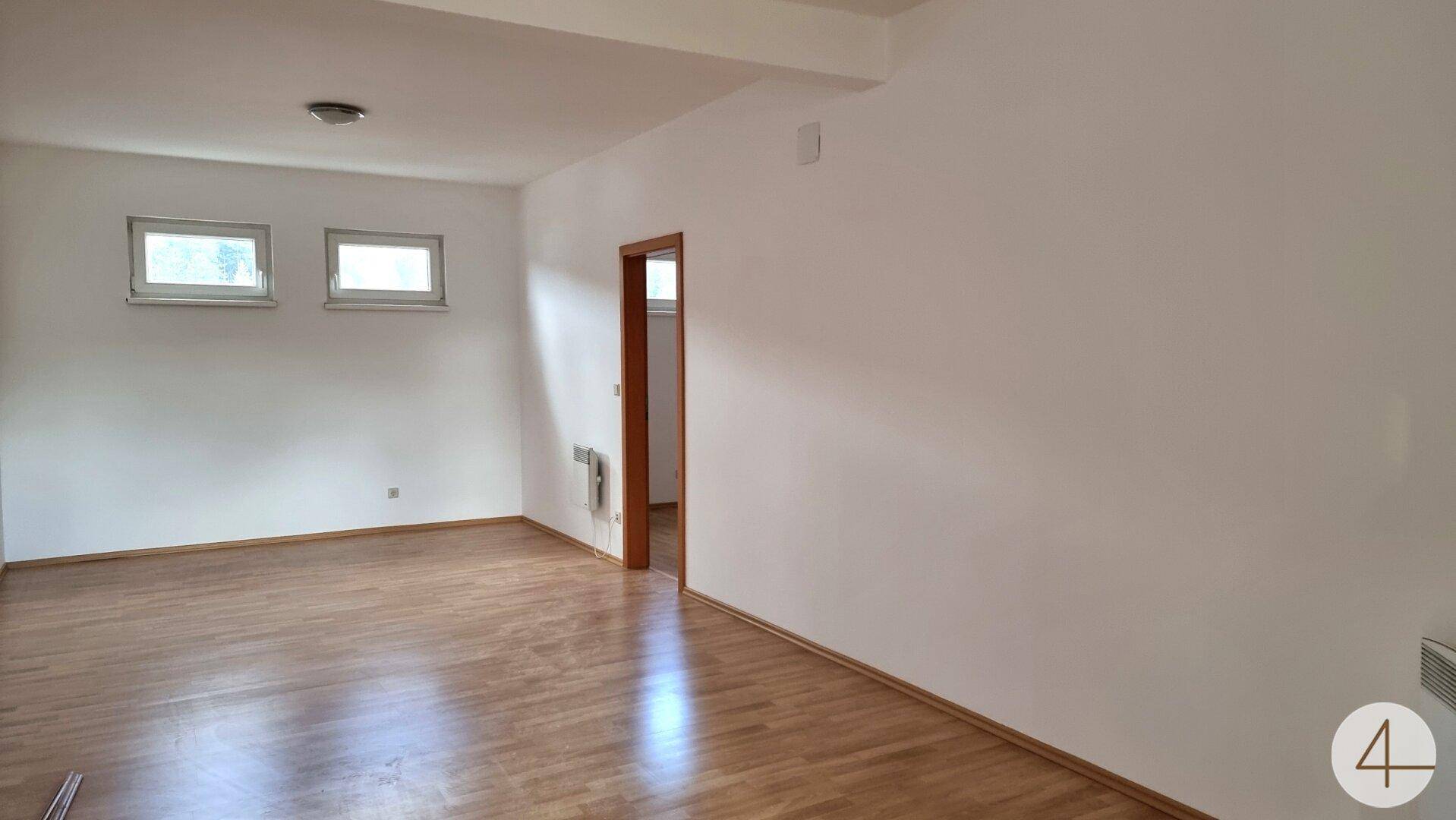 Heller Flur oder Durchgangsbereich mit Laminatboden und weißen Wänden, der zu weiteren Räumen führt.