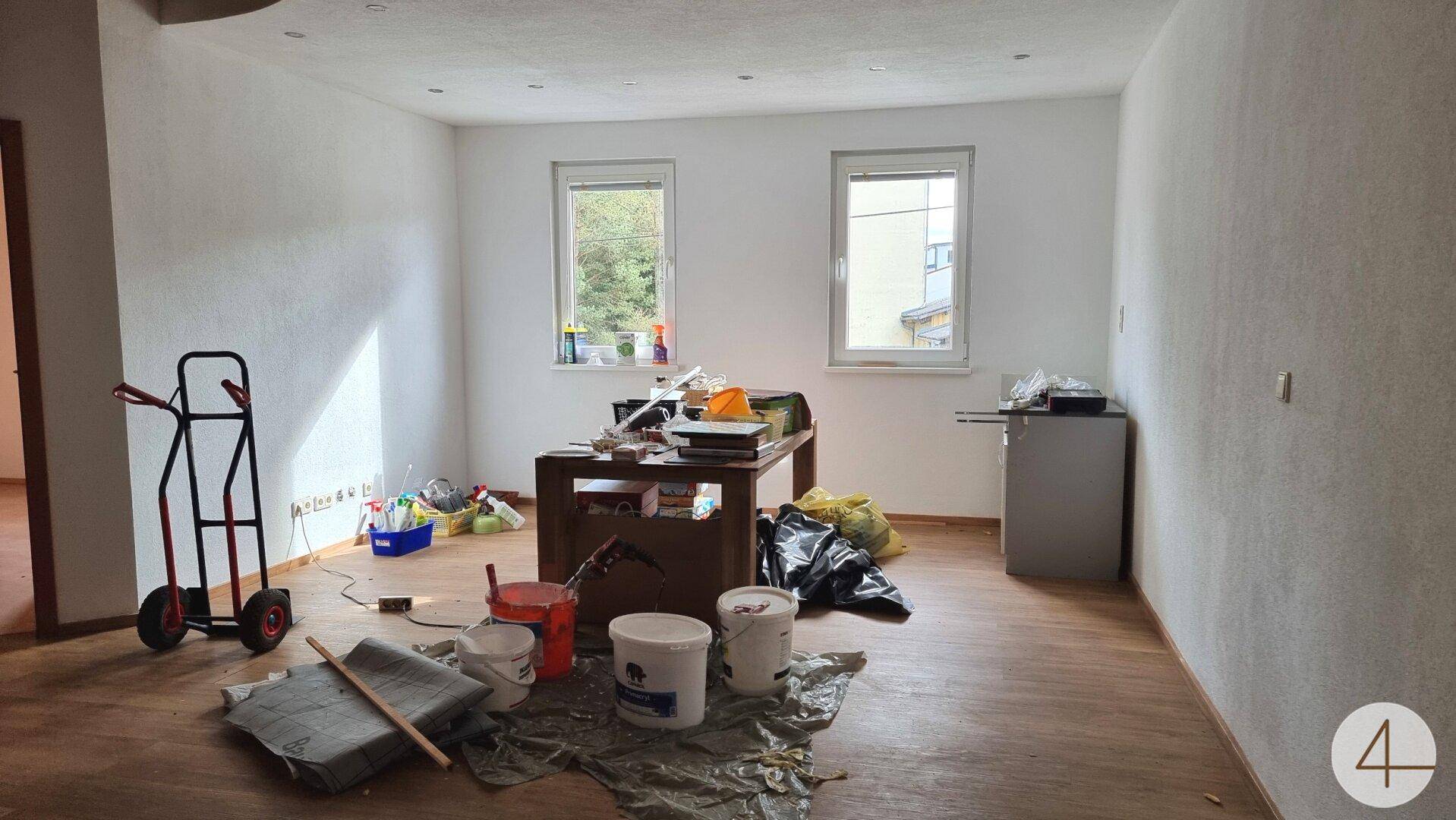 Geräumiger Raum in Renovierung mit Laminatboden und zwei Fenstern, die viel Tageslicht bieten.