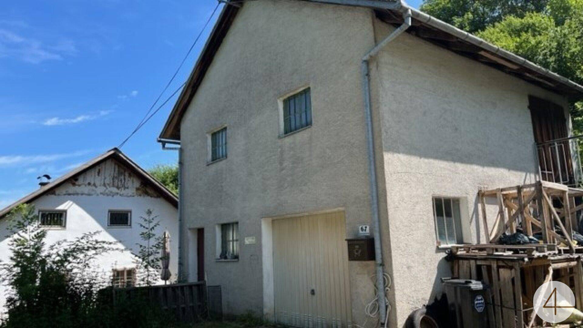 Seitenansicht des alten Hauses mit Garagentor und einer provisorischen Holzkonstruktion im Außenbereich.