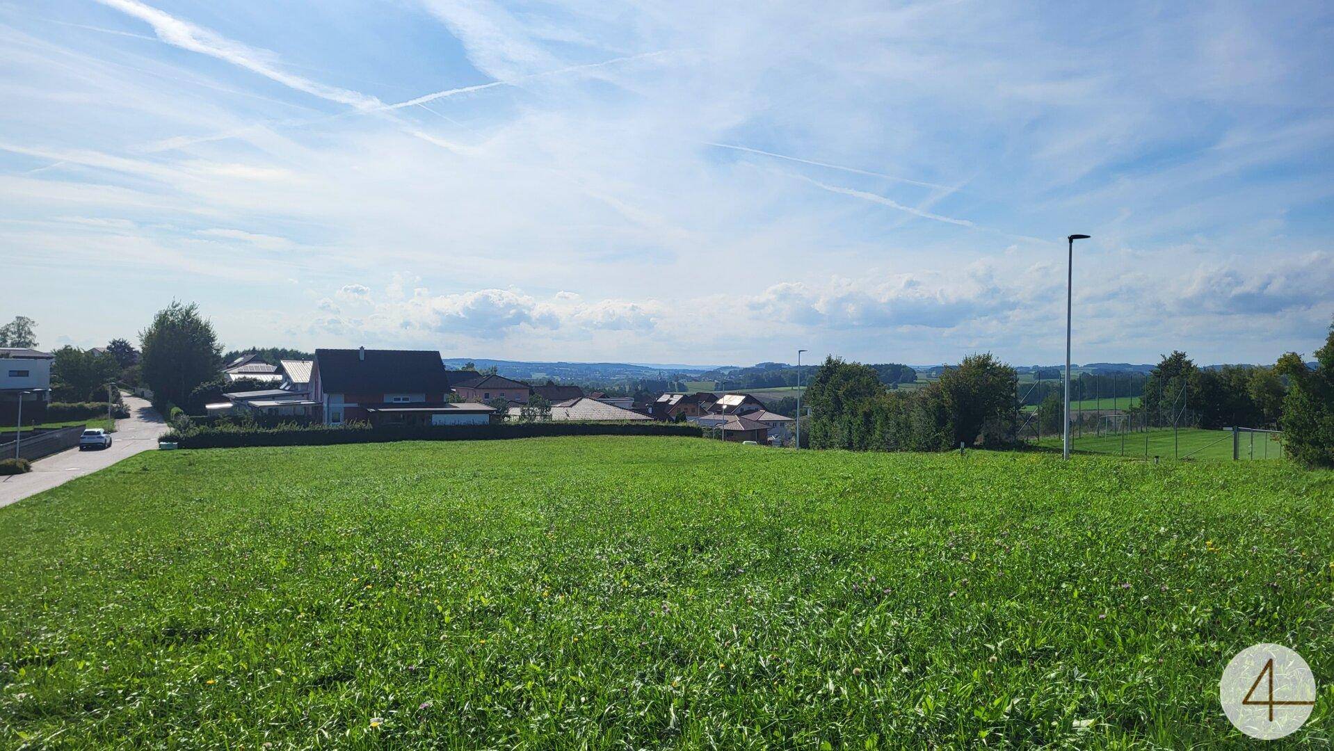 Grüne Wiese mit Blick auf umliegende Häuser und die weite Landschaft.