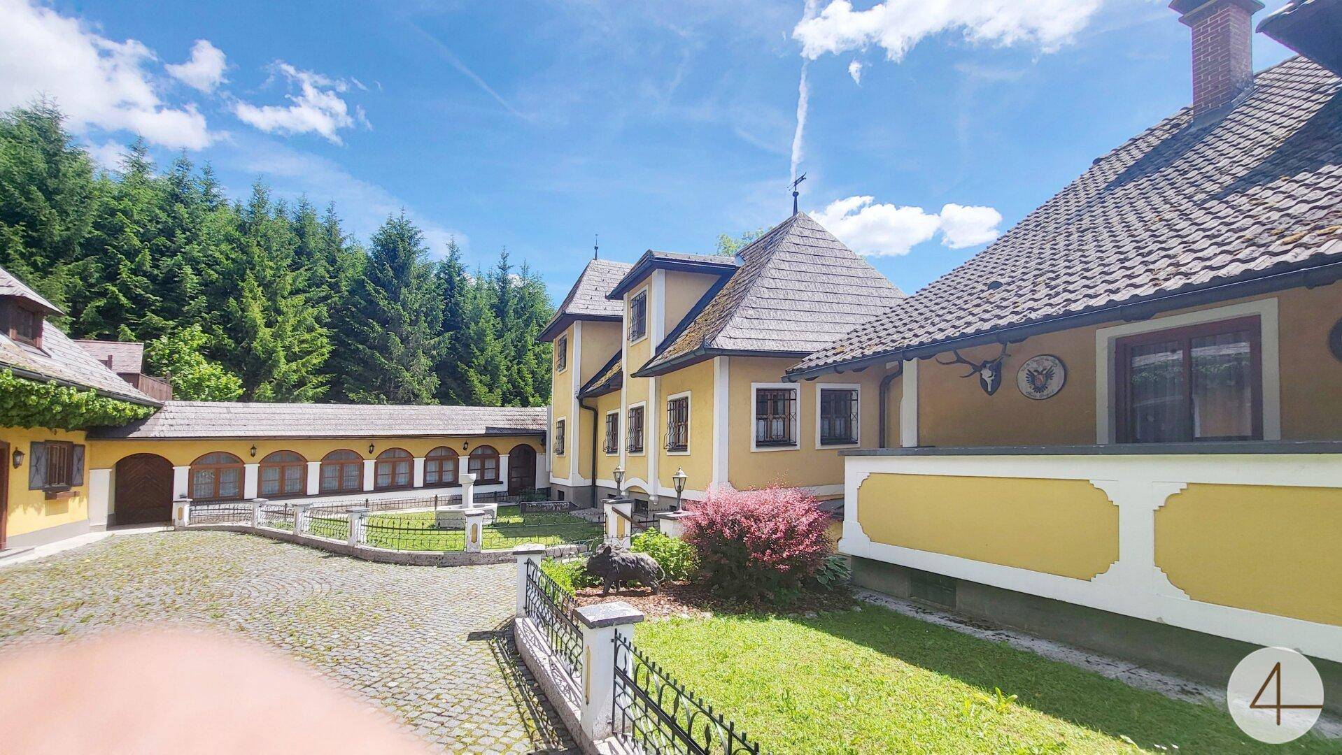 Weitläufiges historisches Anwesen mit mehreren Gebäudeteilen und gepflastertem Innenhof.