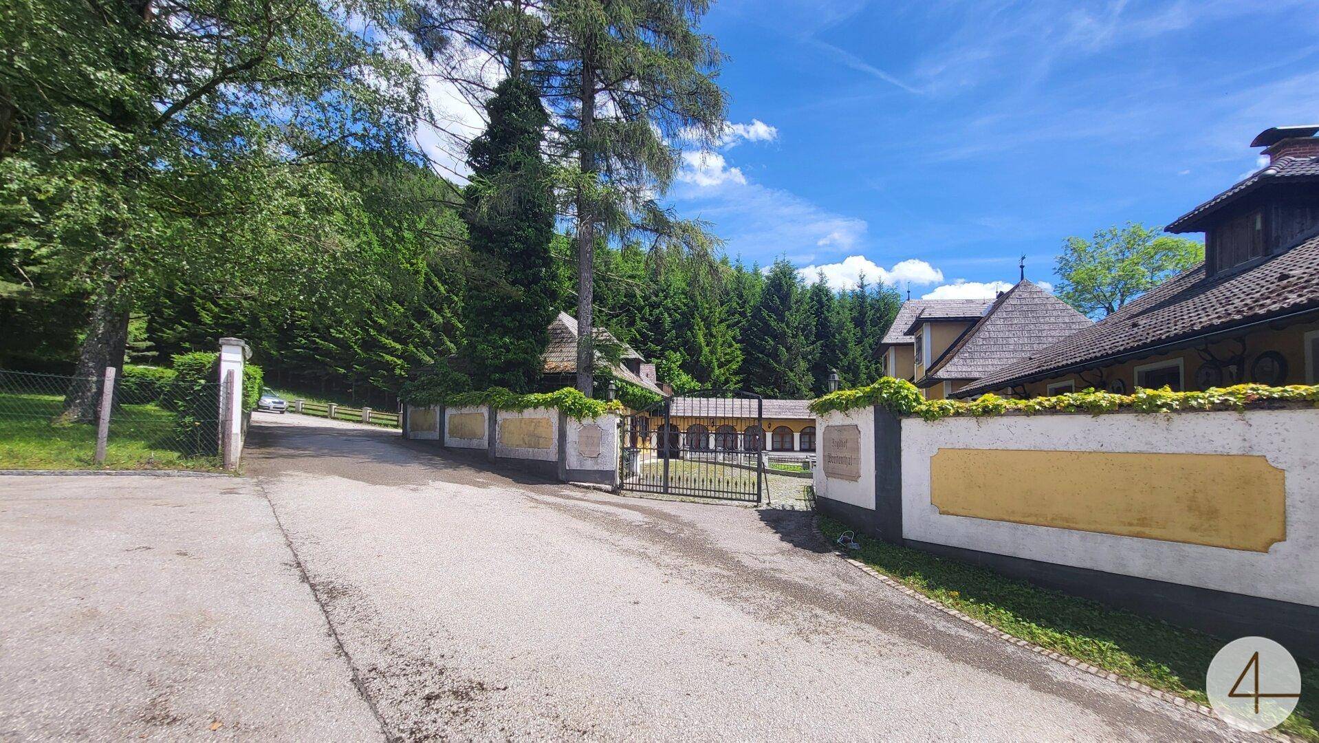 Historisches Eingangstor zum Anwesen mit gepflegter Zufahrt und umgebender Natur.