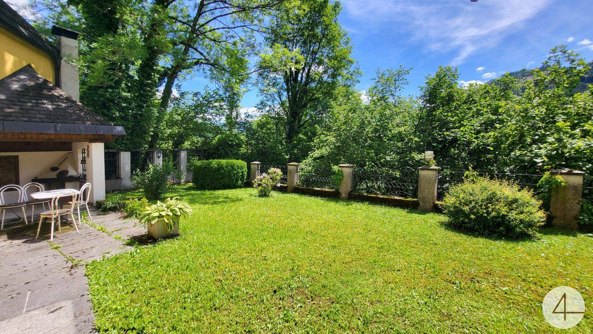 Weitläufiger Gartenbereich mit gepflegtem Rasen und altem Baumbestand.