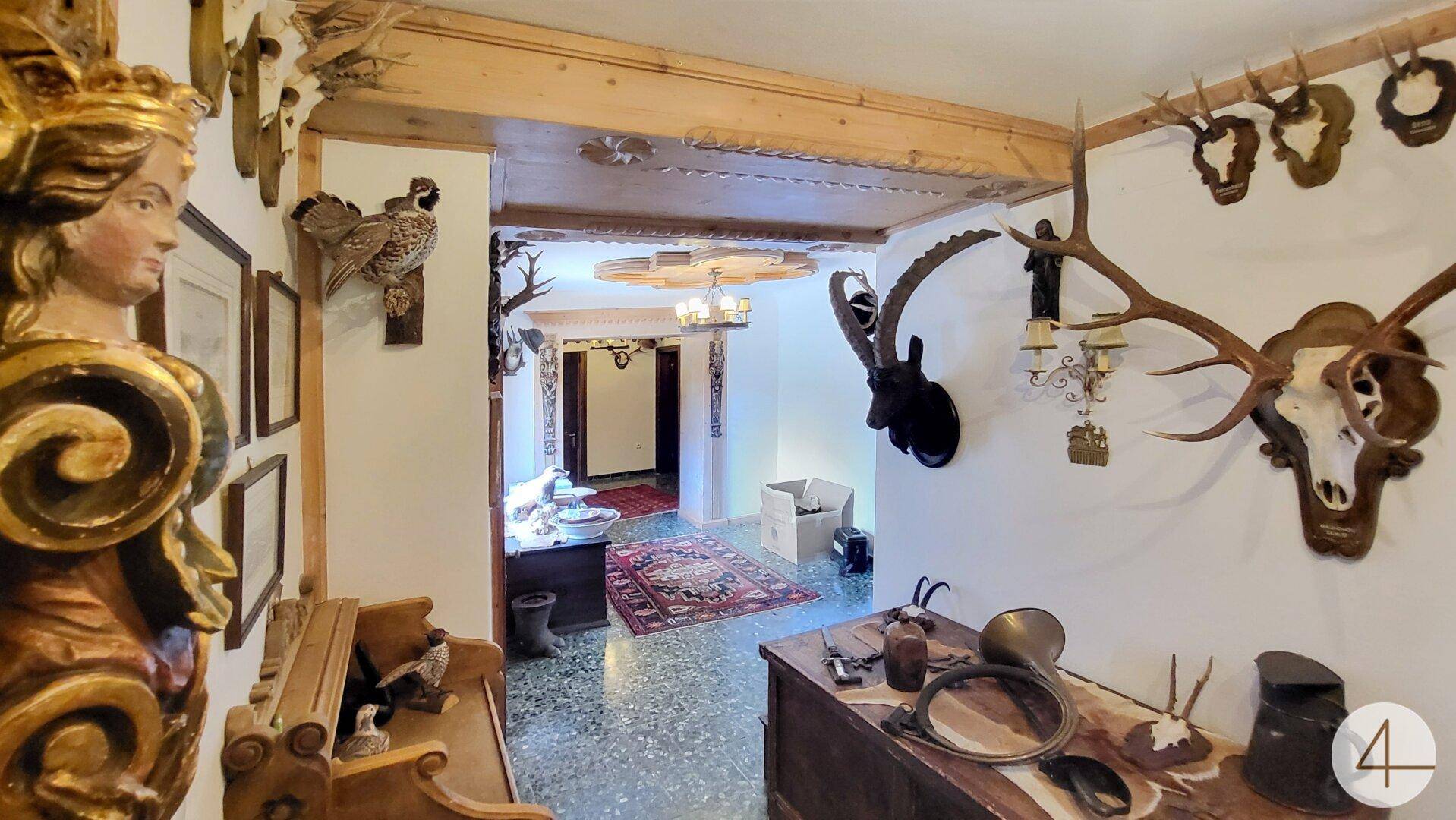 Traditioneller Eingangsbereich mit Holzbalken, Stuckdecke und Jagdtrophäen, der einen rustikalen Charme versprüht.