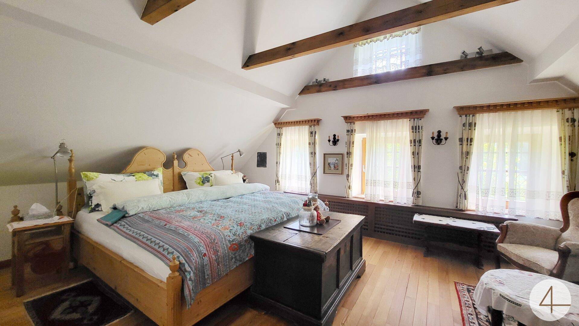 Gemütliches Schlafzimmer im Dachgeschoss mit Holzbalken, schrägen Decken und traditionellem Holzboden.