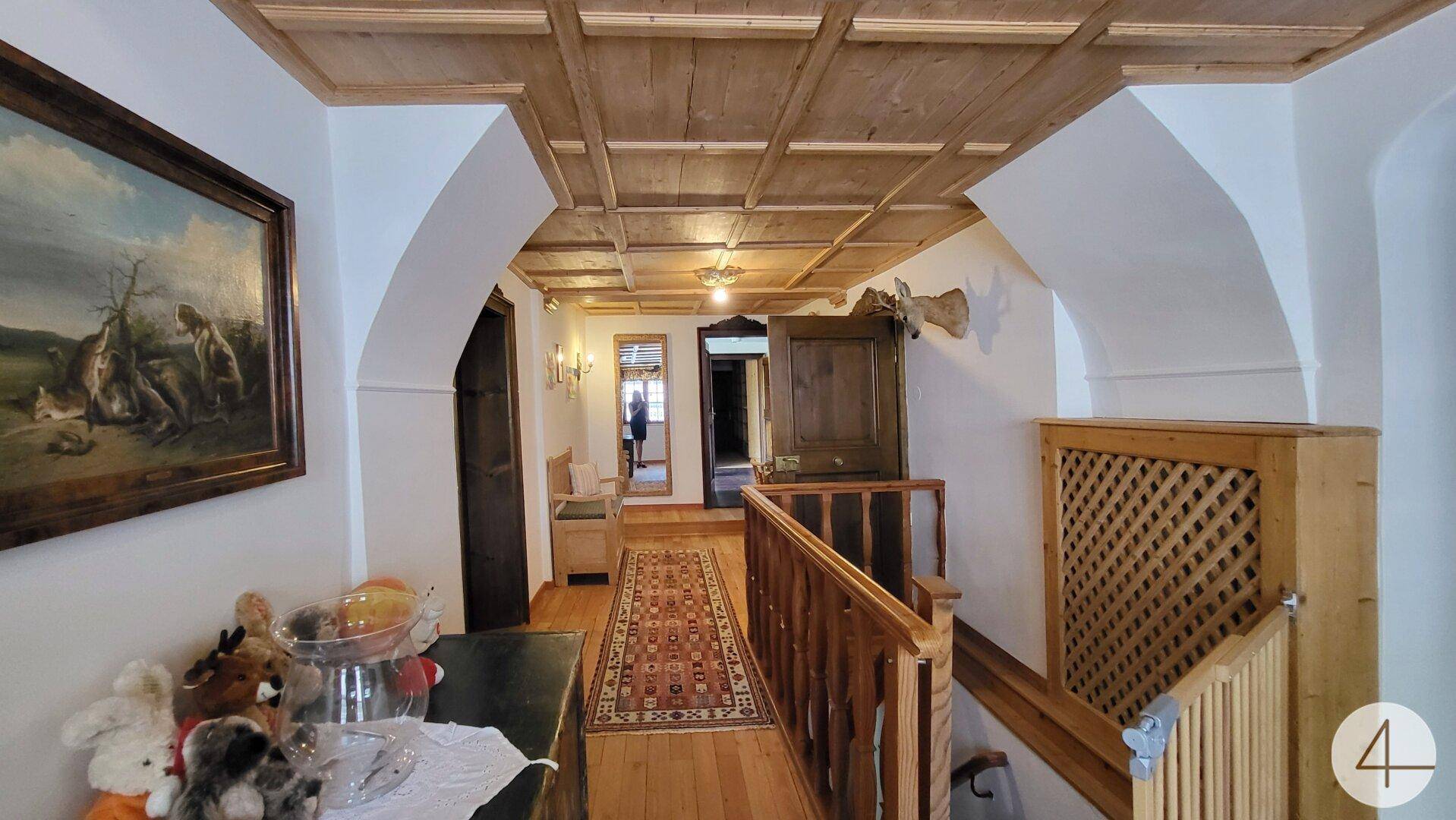 Heller Flur mit Holzvertäfelung, Treppenaufgang und traditioneller Dekoration.