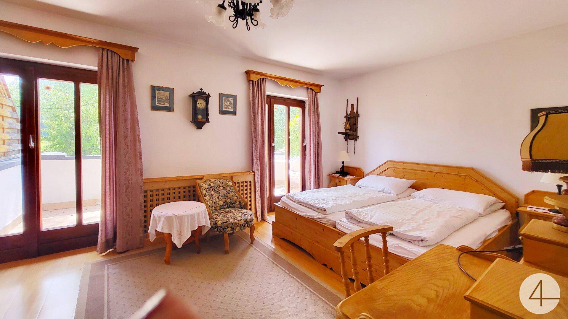 Gemütliches Schlafzimmer mit Doppelbett, Holzmöbeln und direktem Zugang zum Balkon.