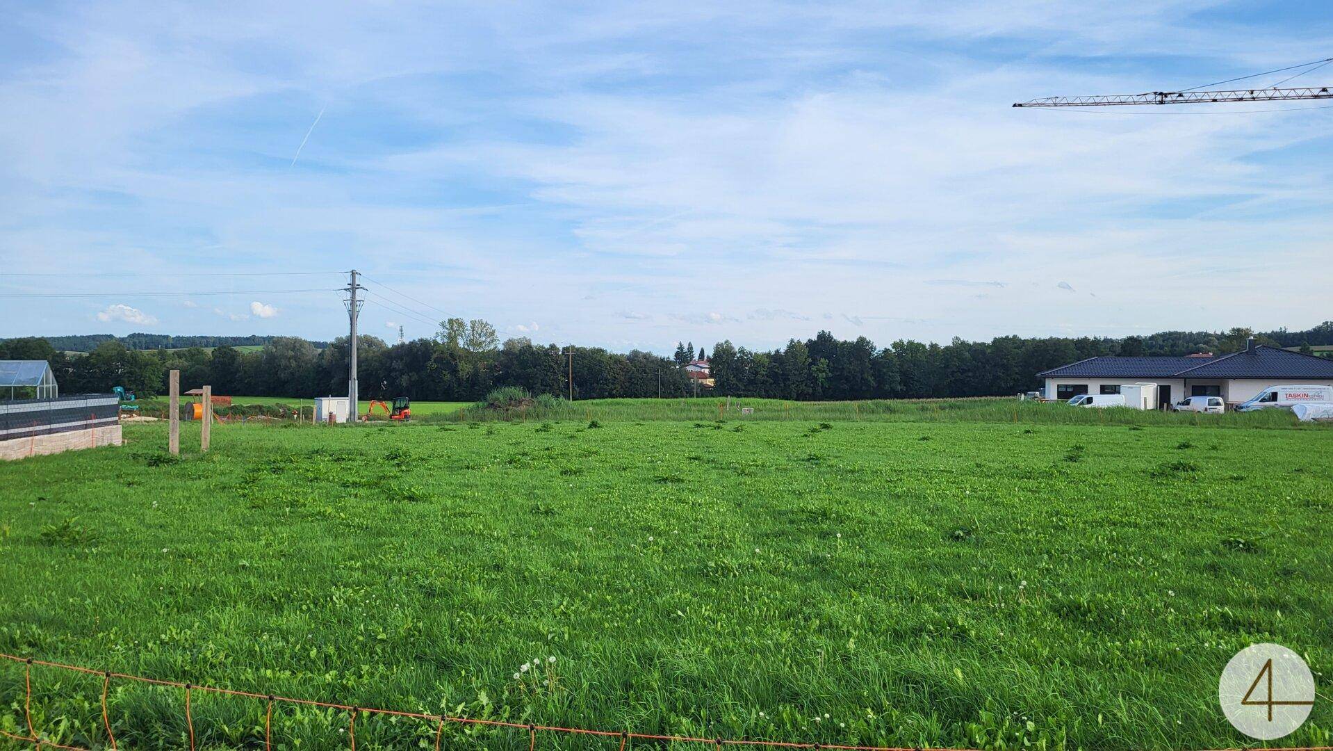 Offenes Feld mit weitem Blick auf die umliegende Landschaft und einige Gebäude in der Ferne.