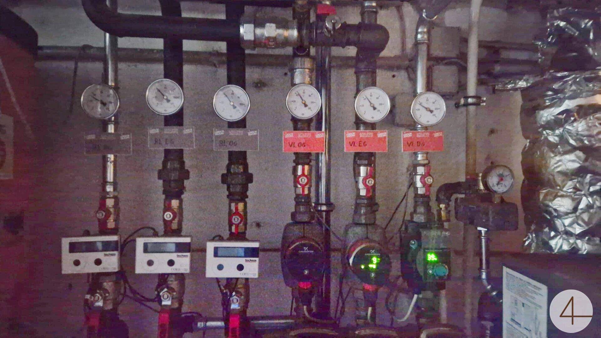 Technischer Raum mit Heizungsrohren, Manometern und Steuerungselementen für die Haustechnik.