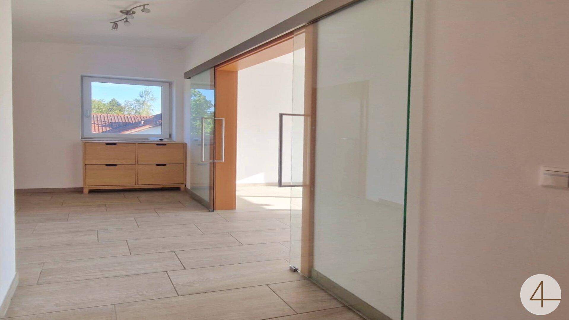 Heller Eingangsbereich mit Fliesenboden, Fenster und einer modernen Glasschiebetür.