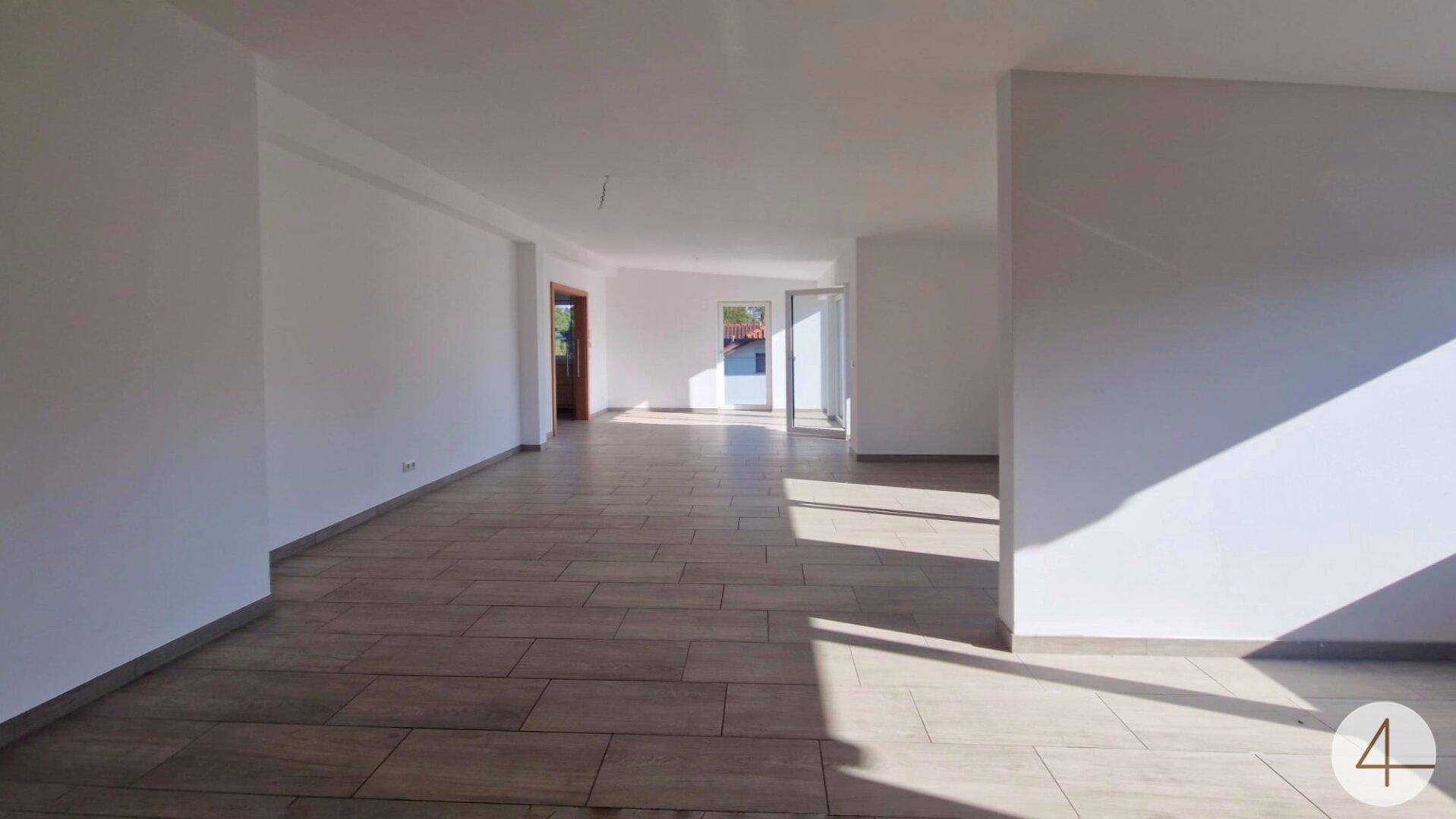 Großer, heller Raum mit Fliesenboden und viel Tageslicht, ideal für offenes Wohnen.