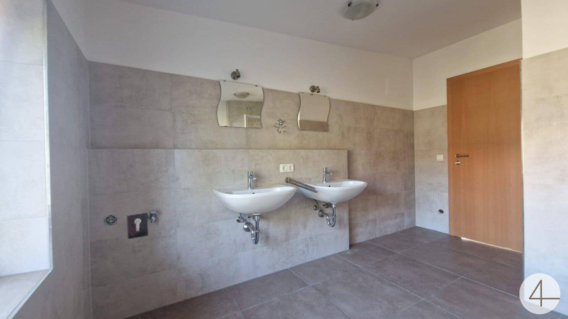Modernes Badezimmer mit zwei Waschbecken, großen Fliesen und viel Platz.