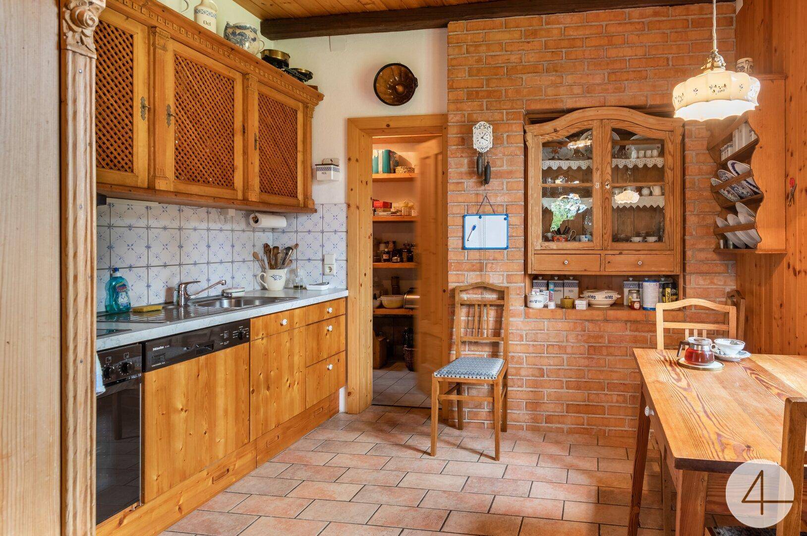 Rustikale Holzküche mit Backsteinwand, gefliestem Boden und integrierten Geräten.