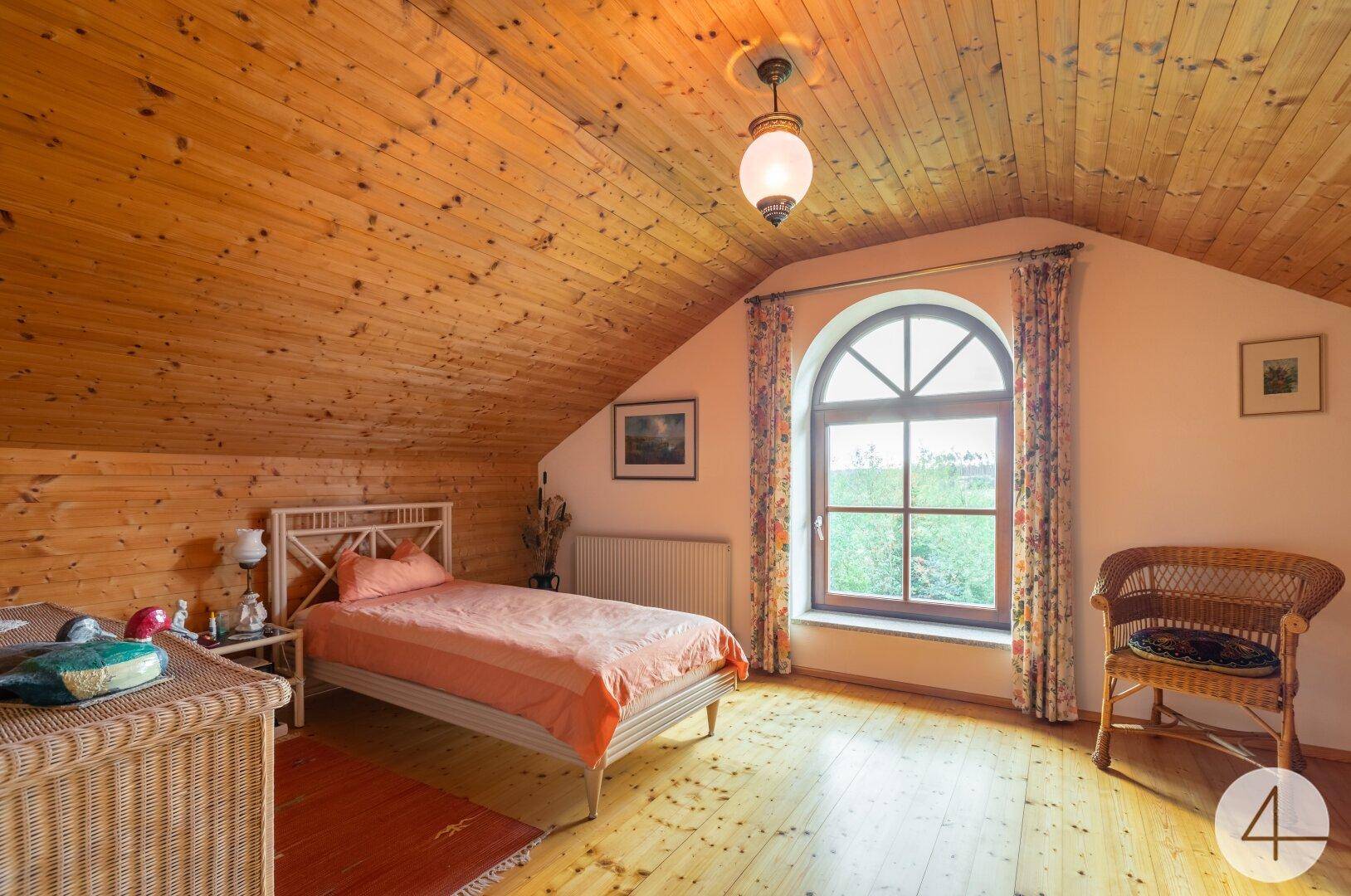 Helles Schlafzimmer im Dachgeschoss mit Holzverkleidung, Einzelbett und Korbmöbeln.
