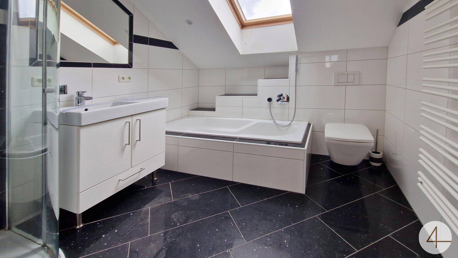 Modernes Badezimmer mit Dachschräge, Badewanne, Dusche und dunklen Fliesenböden.