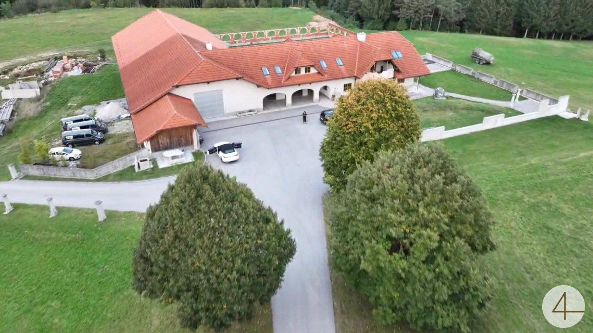 Nahaufnahme aus der Luft zeigt das Anwesen mit Zufahrt, Parkplätzen und umliegenden Grünflächen.