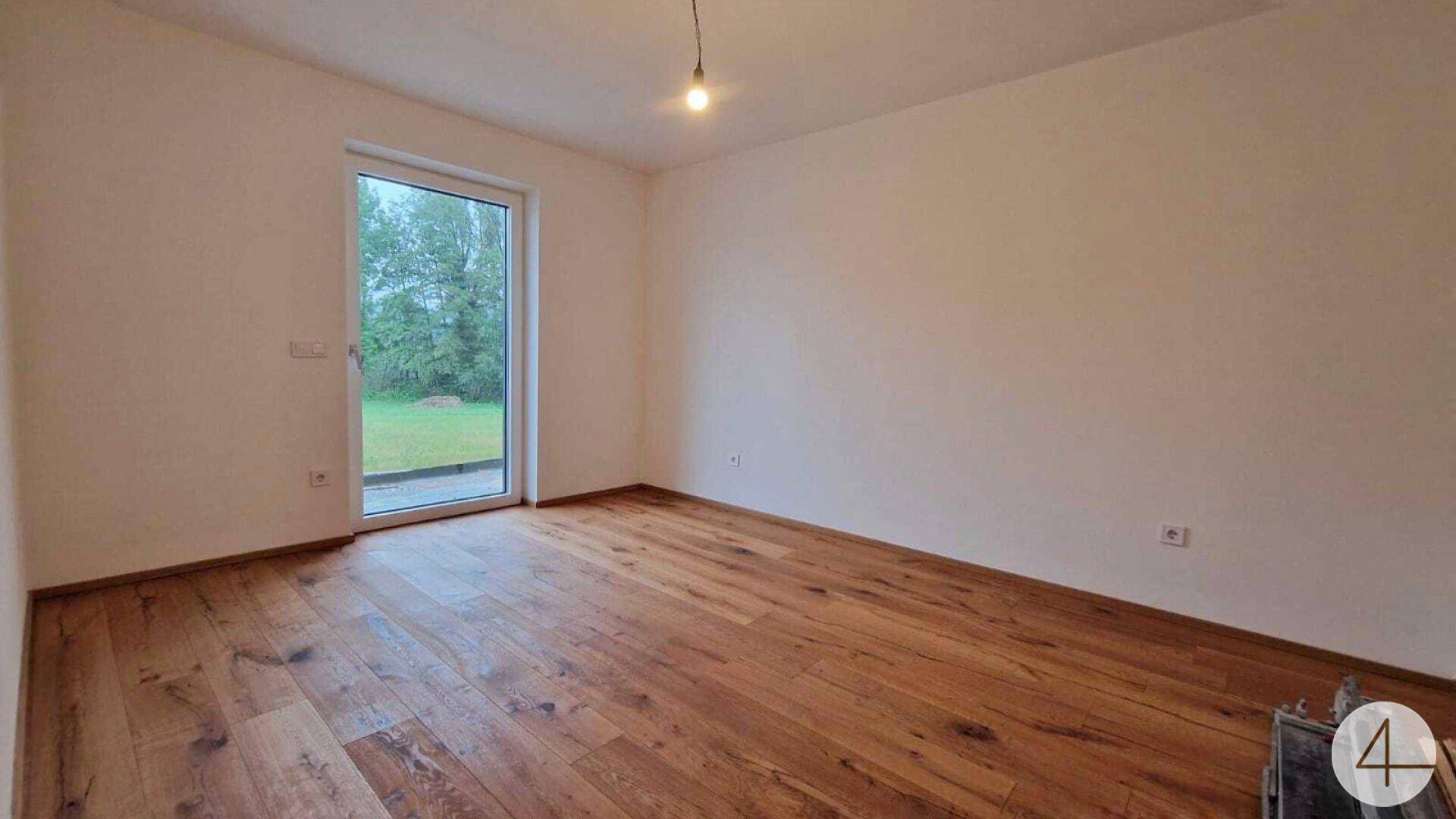 Geräumiges Schlafzimmer mit Holzdielenboden und direktem Zugang zum privaten Gartenbereich.