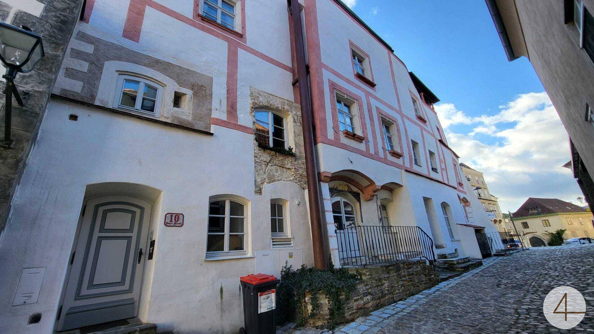 Historische Gasse mit einem alten Gebäude und einem Mülleimer vor der Haustür.