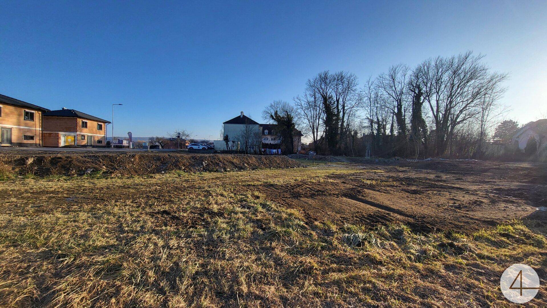 Weitläufiges Baugrundstück mit Blick auf die umliegende Bebauung und Baumbestand.