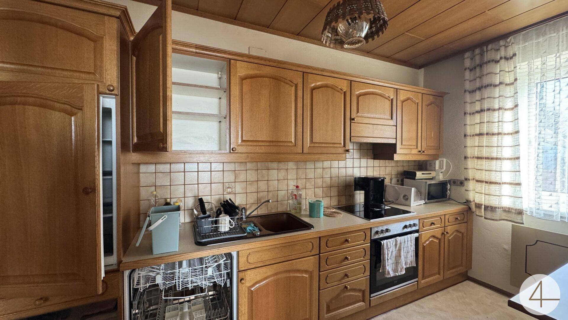 Traditionelle Holzküche mit Einbaugeräten, Fliesenrückwand und Deckenverkleidung aus Holz.