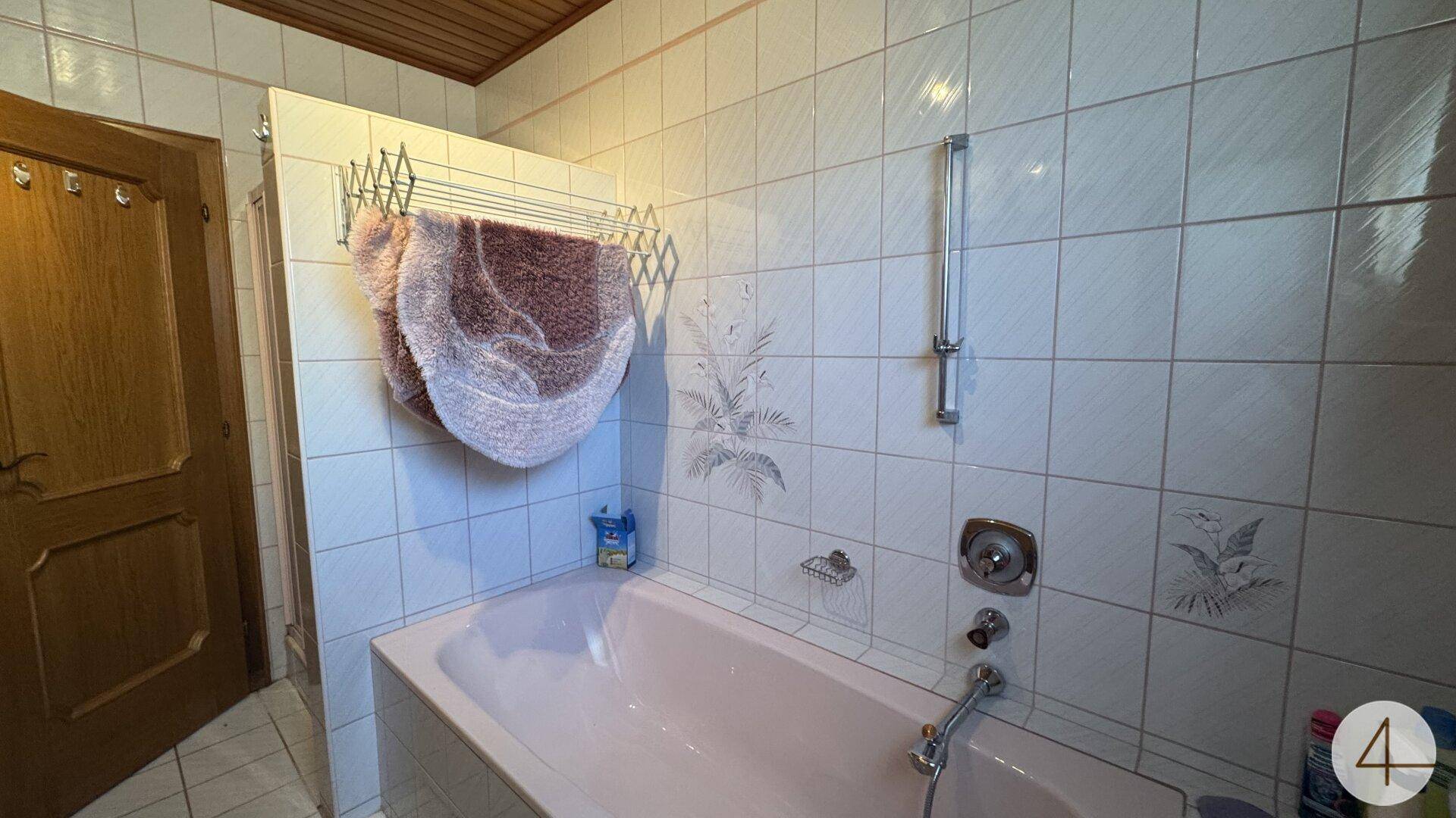 Badezimmer mit rosa Badewanne, weißen Fliesen und Holzdeckenverkleidung.