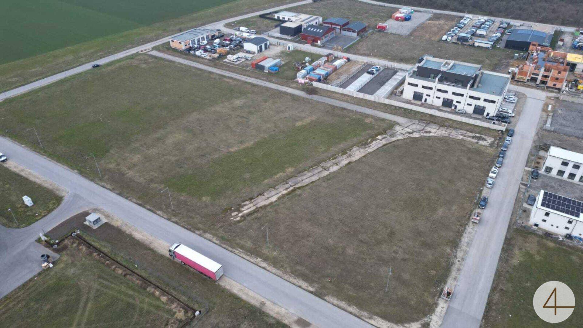 Luftaufnahme eines weitläufigen Gewerbegrundstücks mit bestehenden Gebäuden, unbebauten Flächen und Zufahrtsstraßen.