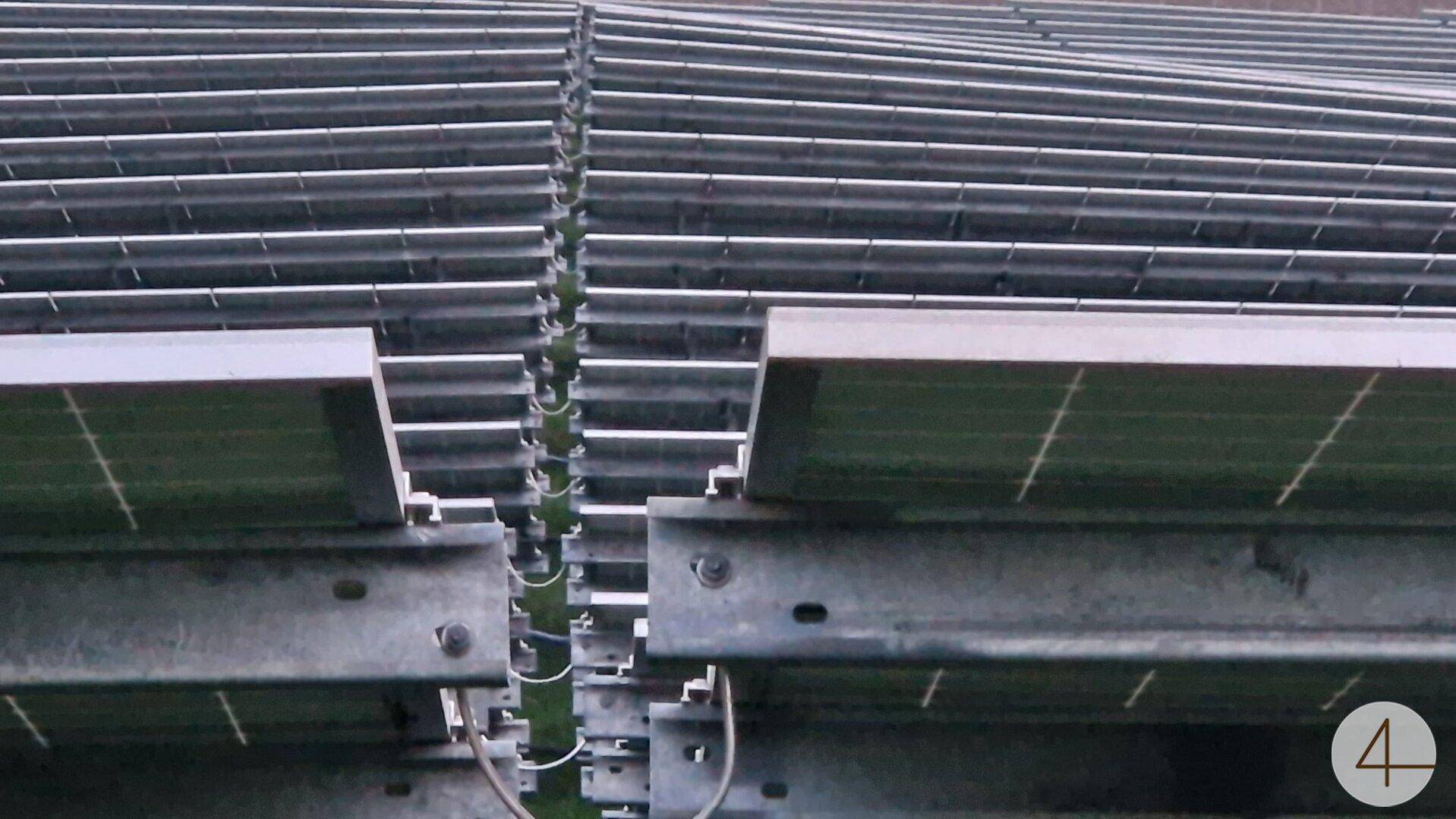 Nahaufnahme der Unterseite von Solarmodulen mit Metallrahmen und Verkabelung.
