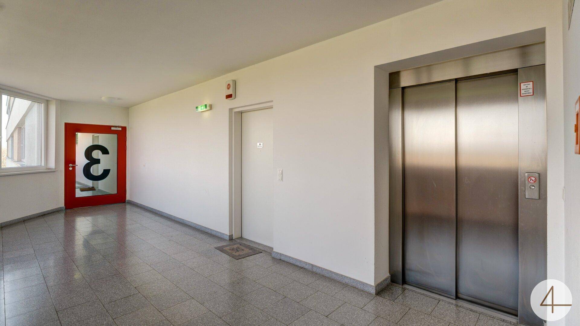 Moderner Flur mit Aufzug und Zugang zu den Wohnungen, hell und funktional gestaltet.
