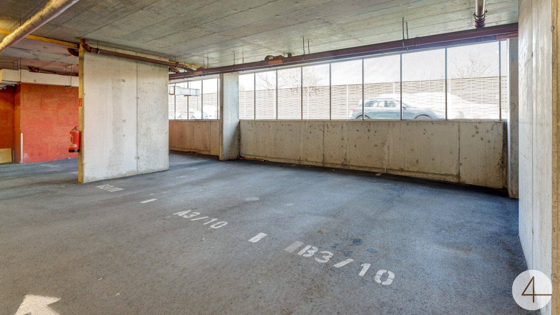 Geräumiger Tiefgaragenstellplatz mit Betonboden und natürlichem Lichteinfall durch Fenster.
