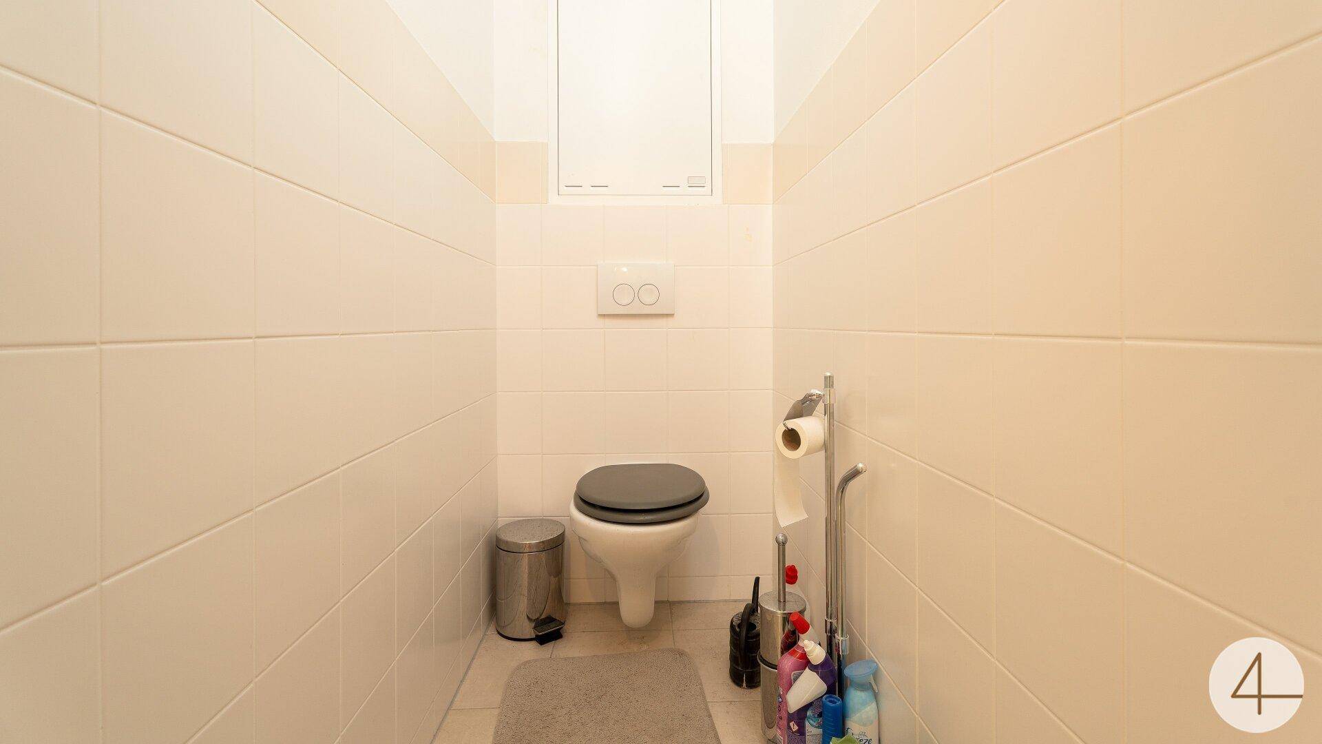 Separates Gäste-WC mit Wand-WC und hellen Fliesen, funktional und pflegeleicht.