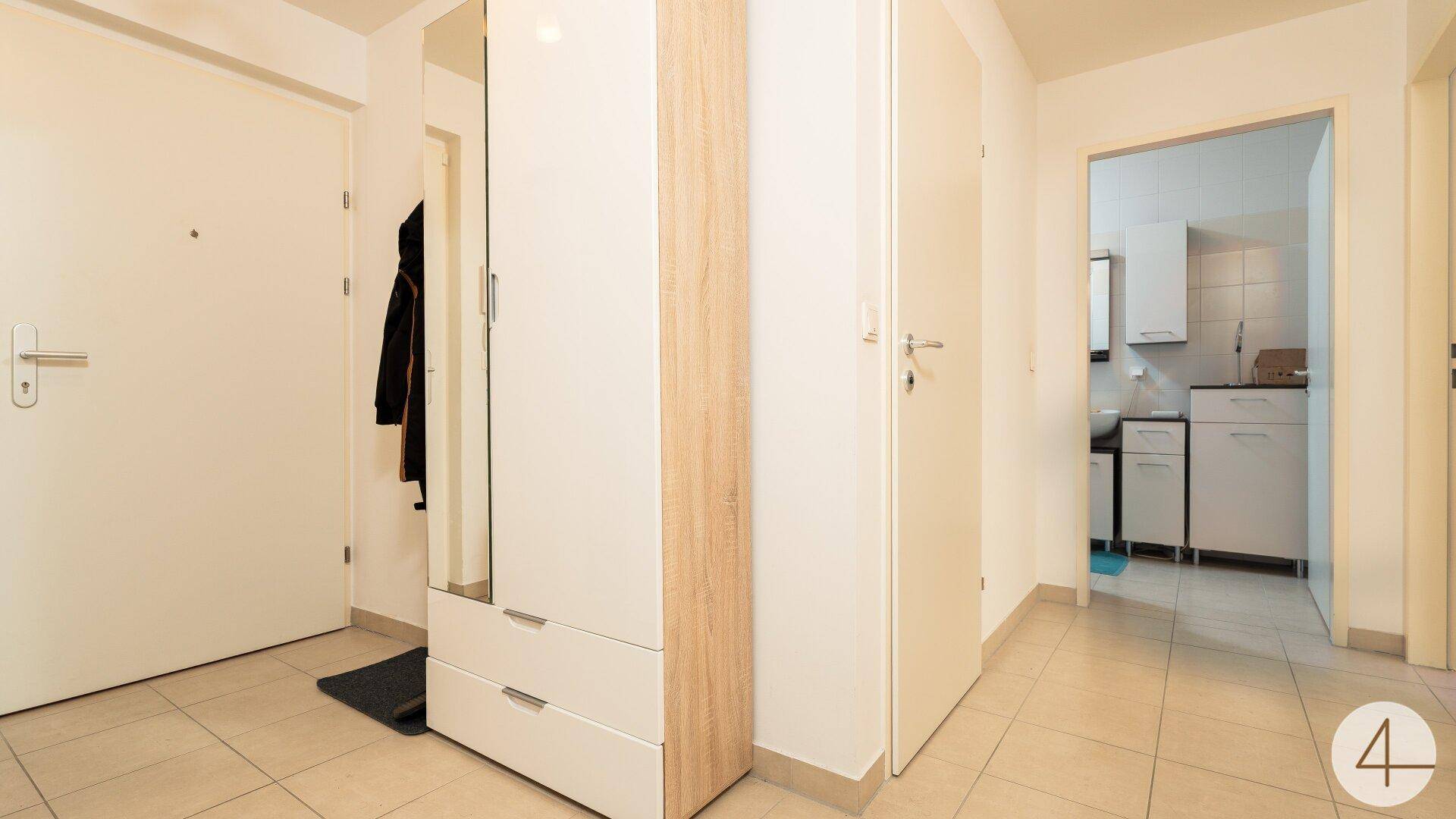 Heller Flur mit Fliesenboden und Zugang zu verschiedenen Räumen, inklusive Badezimmer.