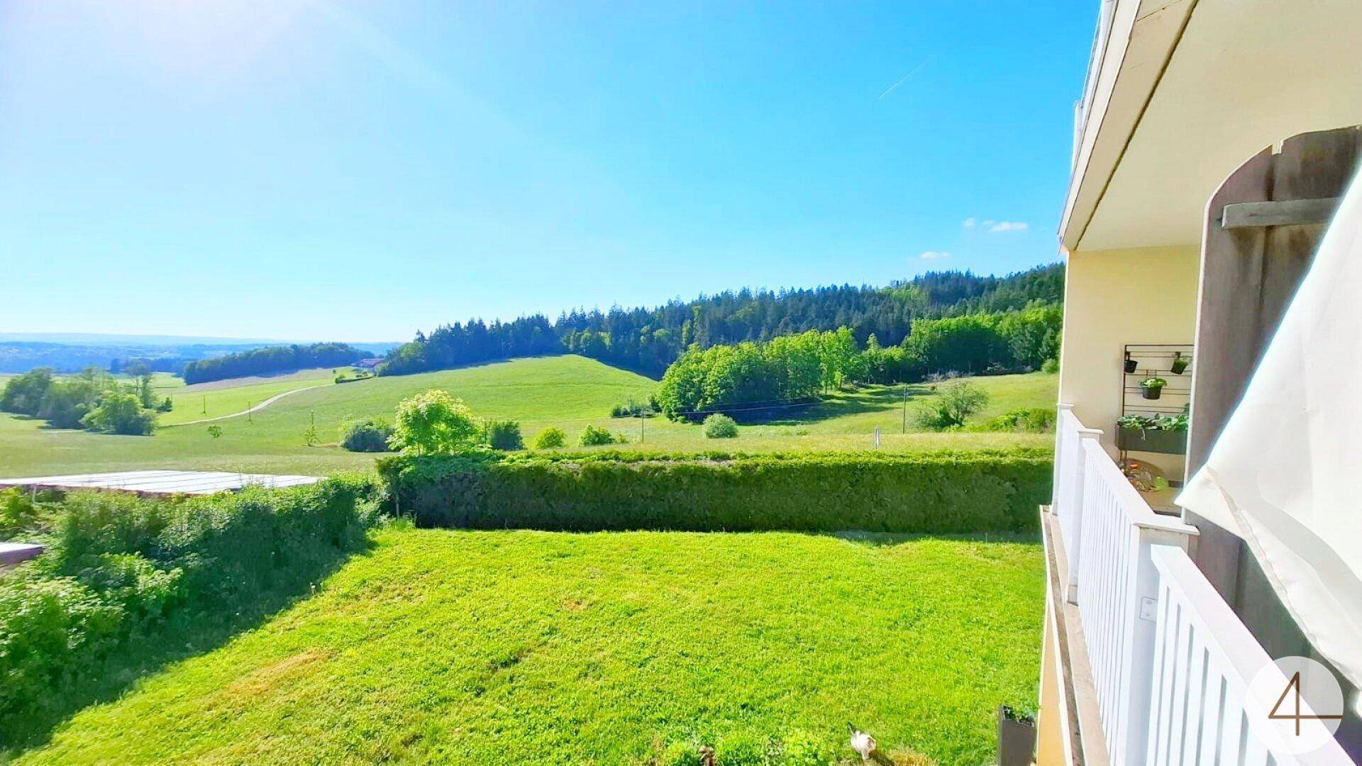 Balkon mit weitem Blick über die grüne Landschaft und die umliegenden Hügel.