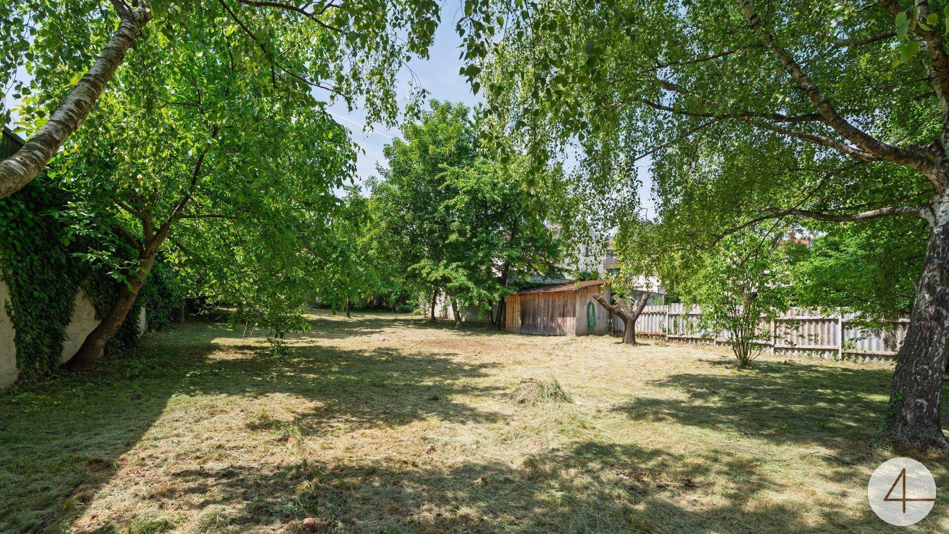 Weitläufiger Garten mit altem Baumbestand und Rasenfläche, umgeben von einer natürlichen Hecke.
