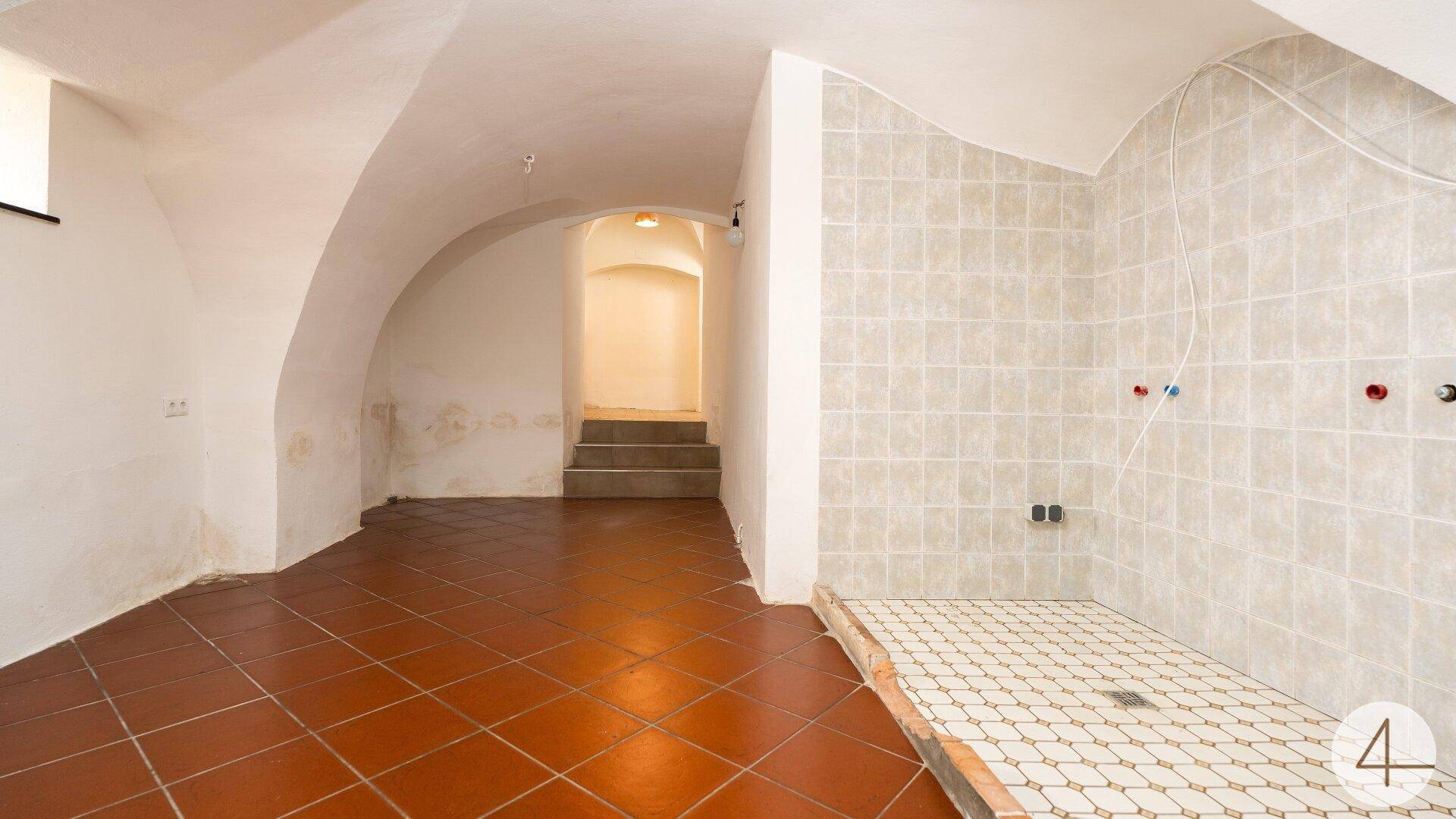 Badezimmer im Rohbau mit Terrakotta-Fliesenboden und vorbereiteter Duschfläche unter Gewölbedecke.