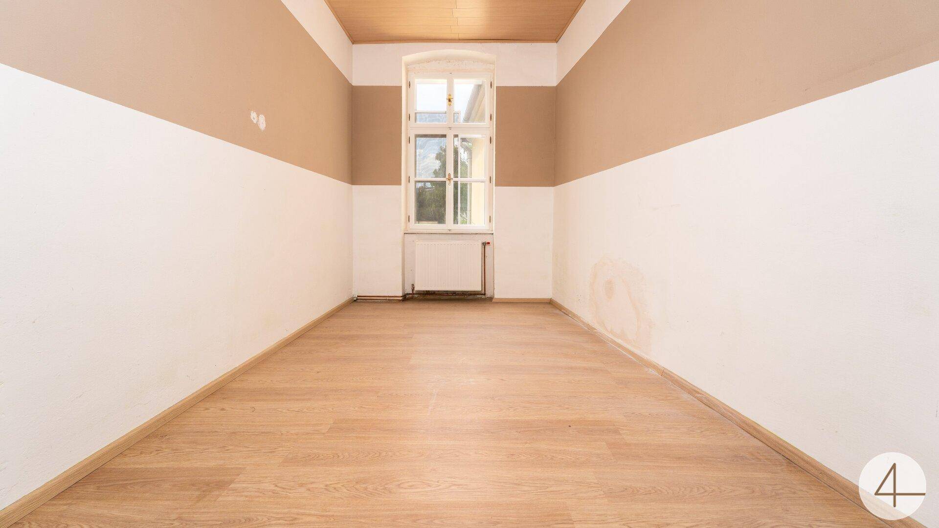 Schlafzimmer mit hellem Laminatboden, zweifarbigen Wänden und einem großen Fenster für viel Tageslicht.