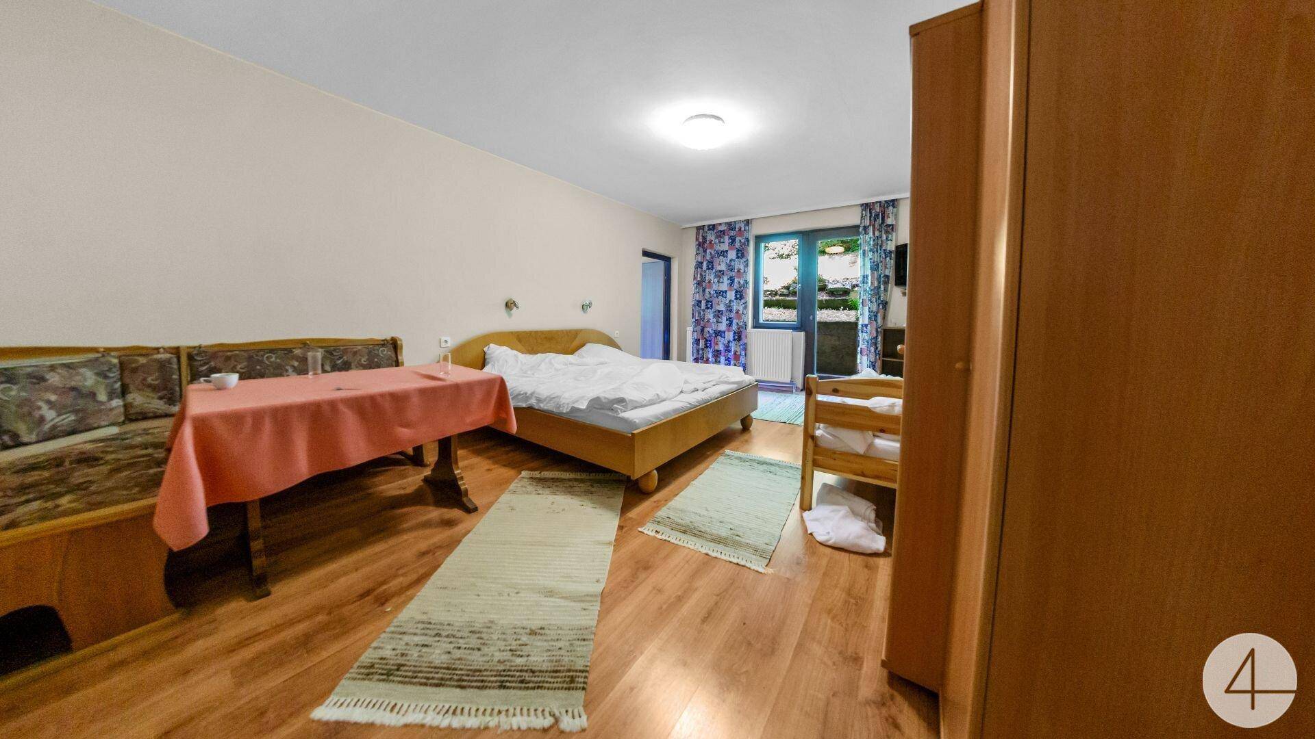 Geräumiges Schlafzimmer mit Doppelbett, Holzboden und Zugang zu einem Balkon.