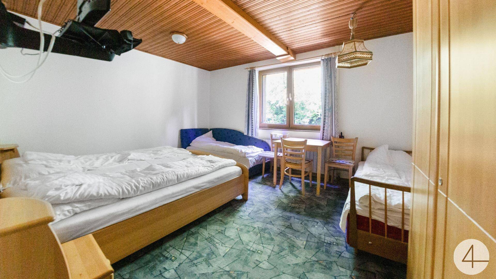 Schlafzimmer mit Doppelbett, Holzboden und Holzdecke, Fenster mit Blick ins Grüne.
