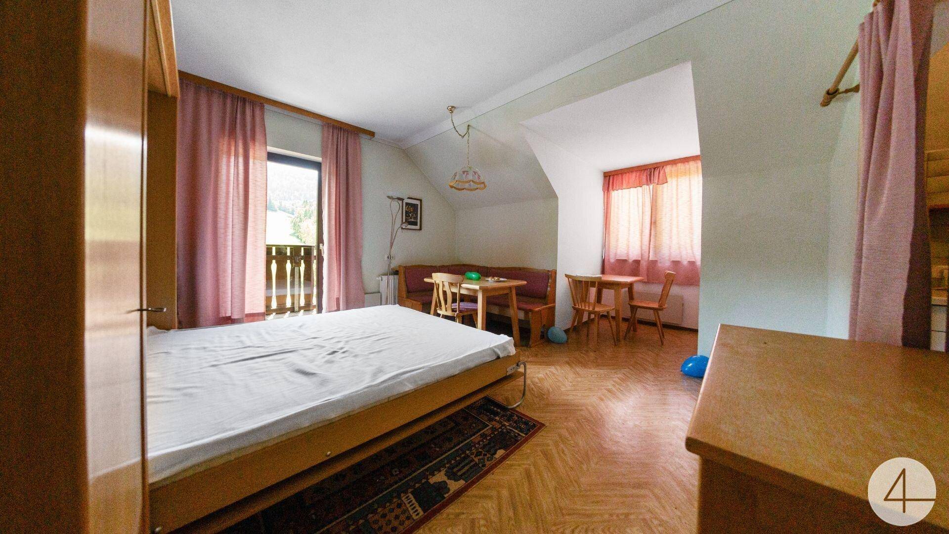 Geräumiges Schlafzimmer mit Doppelbett, Holzboden und Dachschräge, Zugang zu einem Balkon.