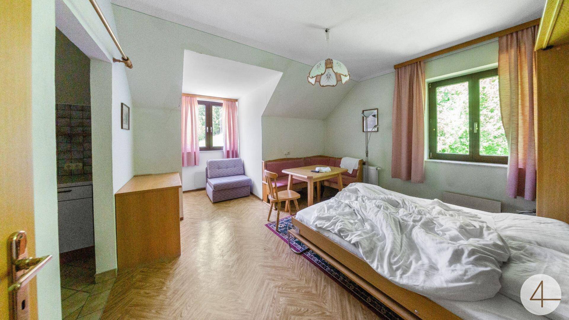 Schlafzimmer mit Doppelbett, Holzboden und Dachschräge, Fenster mit Blick ins Grüne.