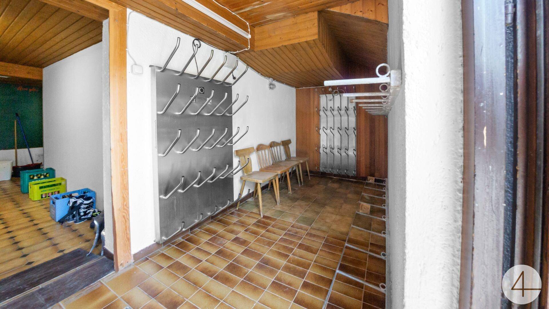 Eingangsbereich mit Garderobe, Holzbänken und Fliesenboden, ideal für Skiausrüstung.