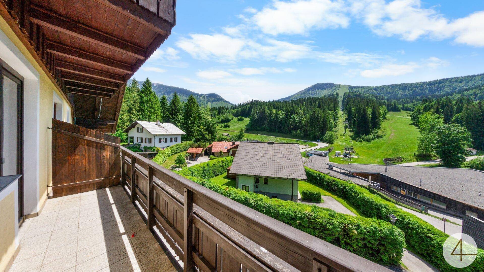 Geräumiger Balkon mit Holzgeländer und Panoramablick auf die grüne Bergwelt.