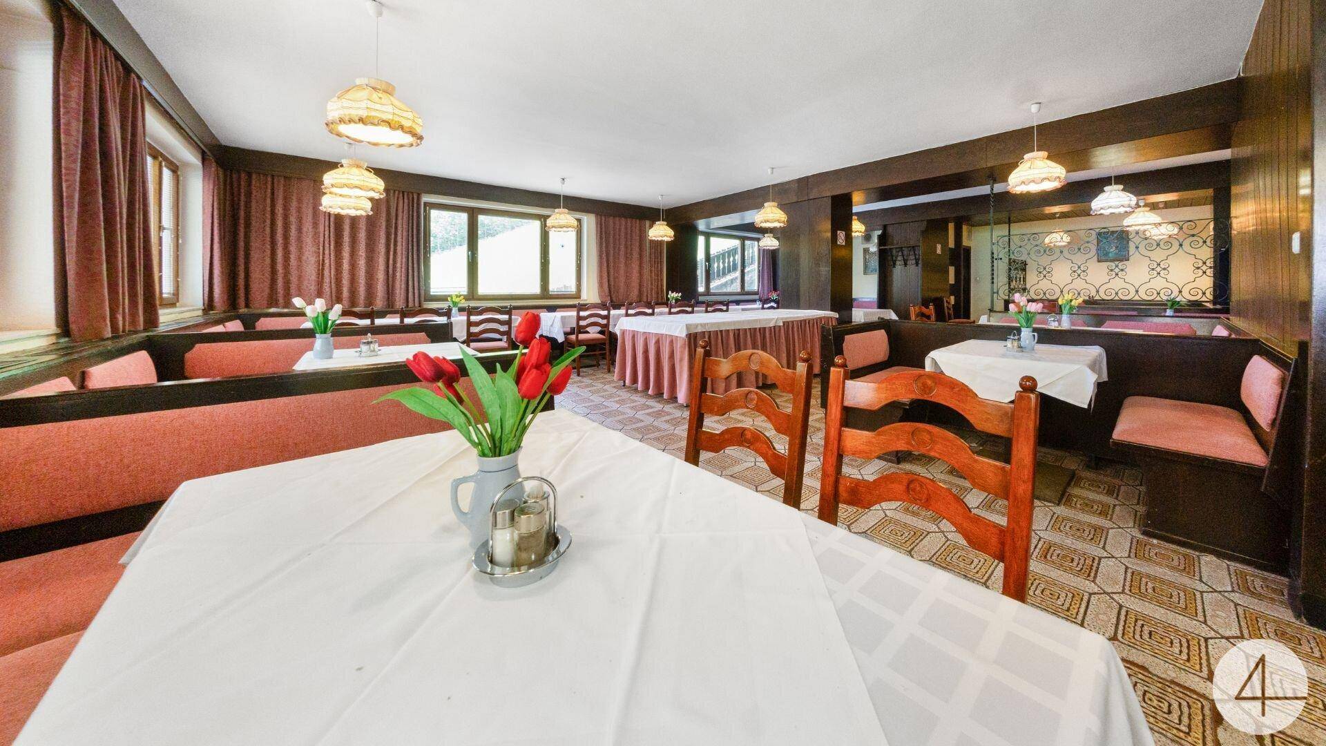 Traditioneller Speisesaal mit Holztäfelung, gepolsterten Bänken und mehreren Tischen.