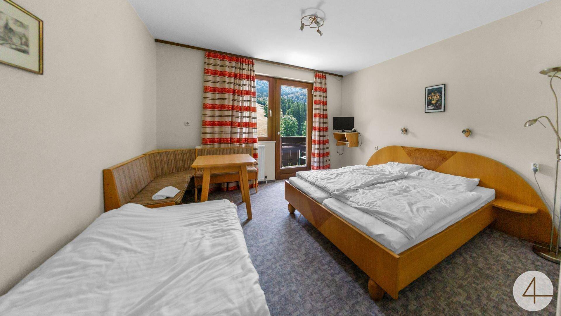 Gemütliches Schlafzimmer mit Doppelbett, Einzelbett und Zugang zu einem Balkon mit Bergblick.