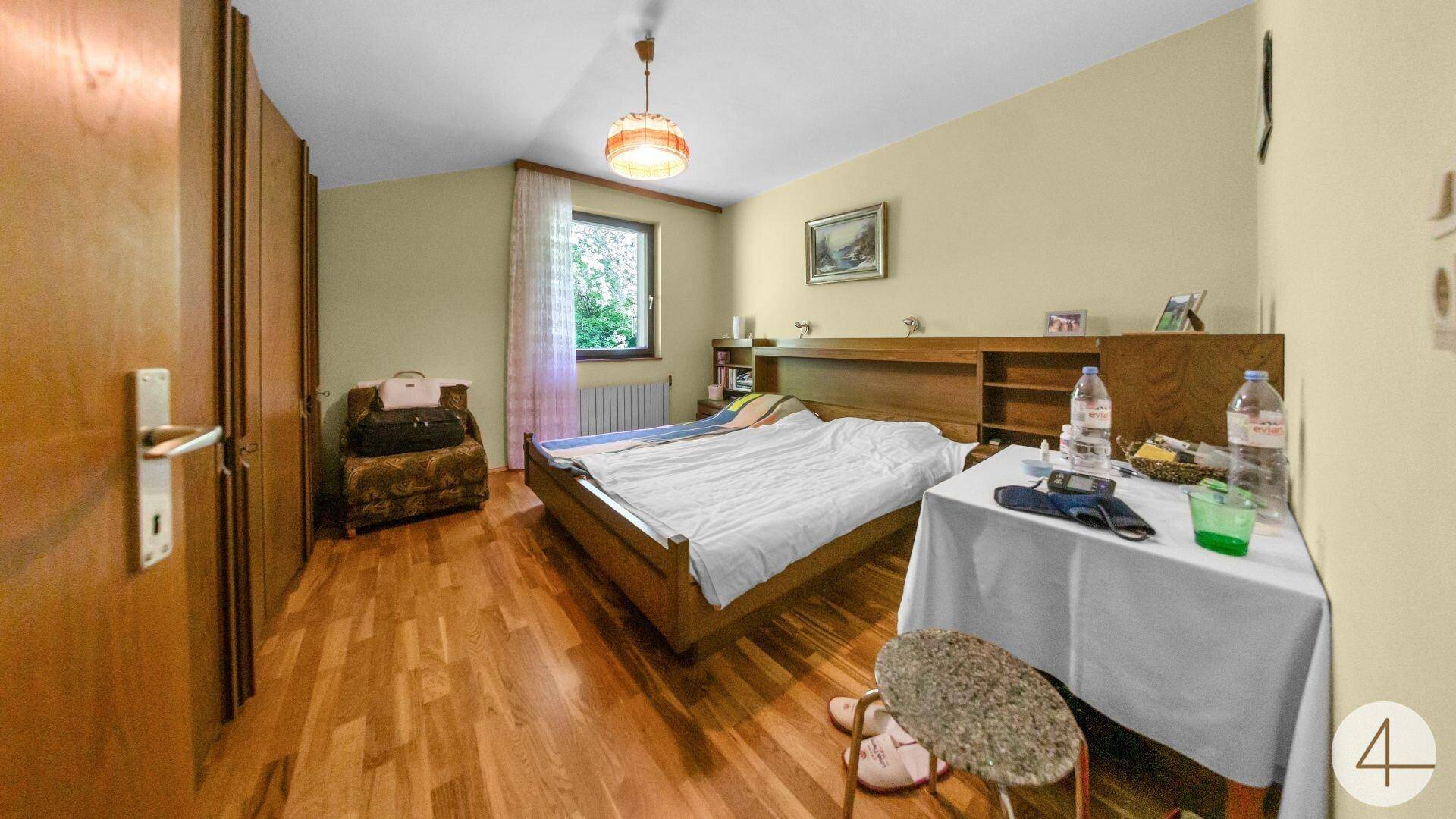 Geräumiges Schlafzimmer mit Doppelbett, Holzboden und einem Fenster mit Blick ins Grüne.