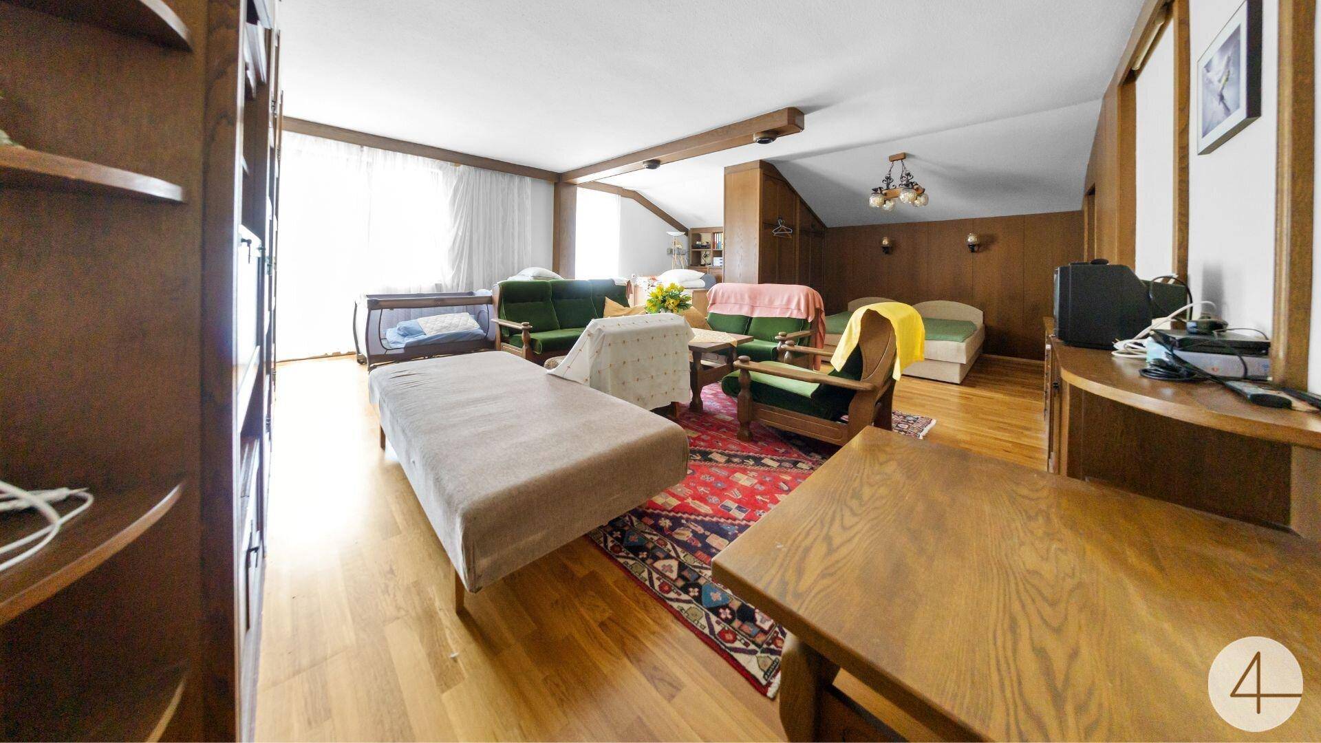 Großes Wohnzimmer mit mehreren Betten, Holzboden und traditioneller Einrichtung.