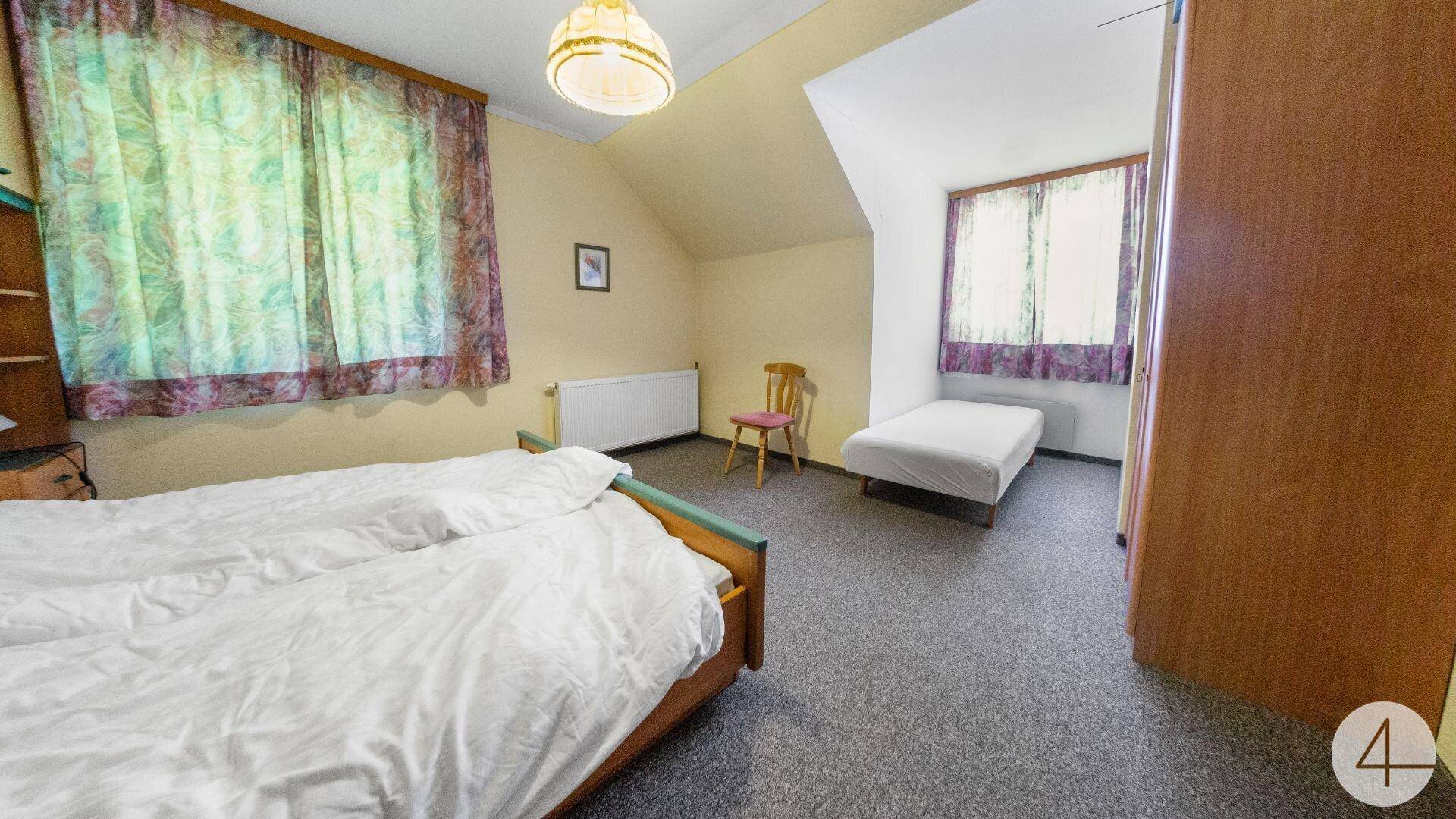 Schlafzimmer mit zwei Einzelbetten, Teppichboden und Dachschräge.
