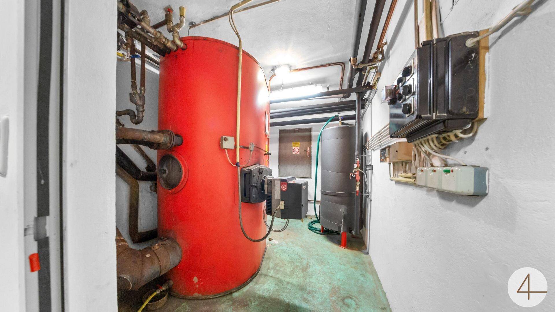 Heizungsraum mit großem Warmwasserspeicher und sichtbaren Rohren.