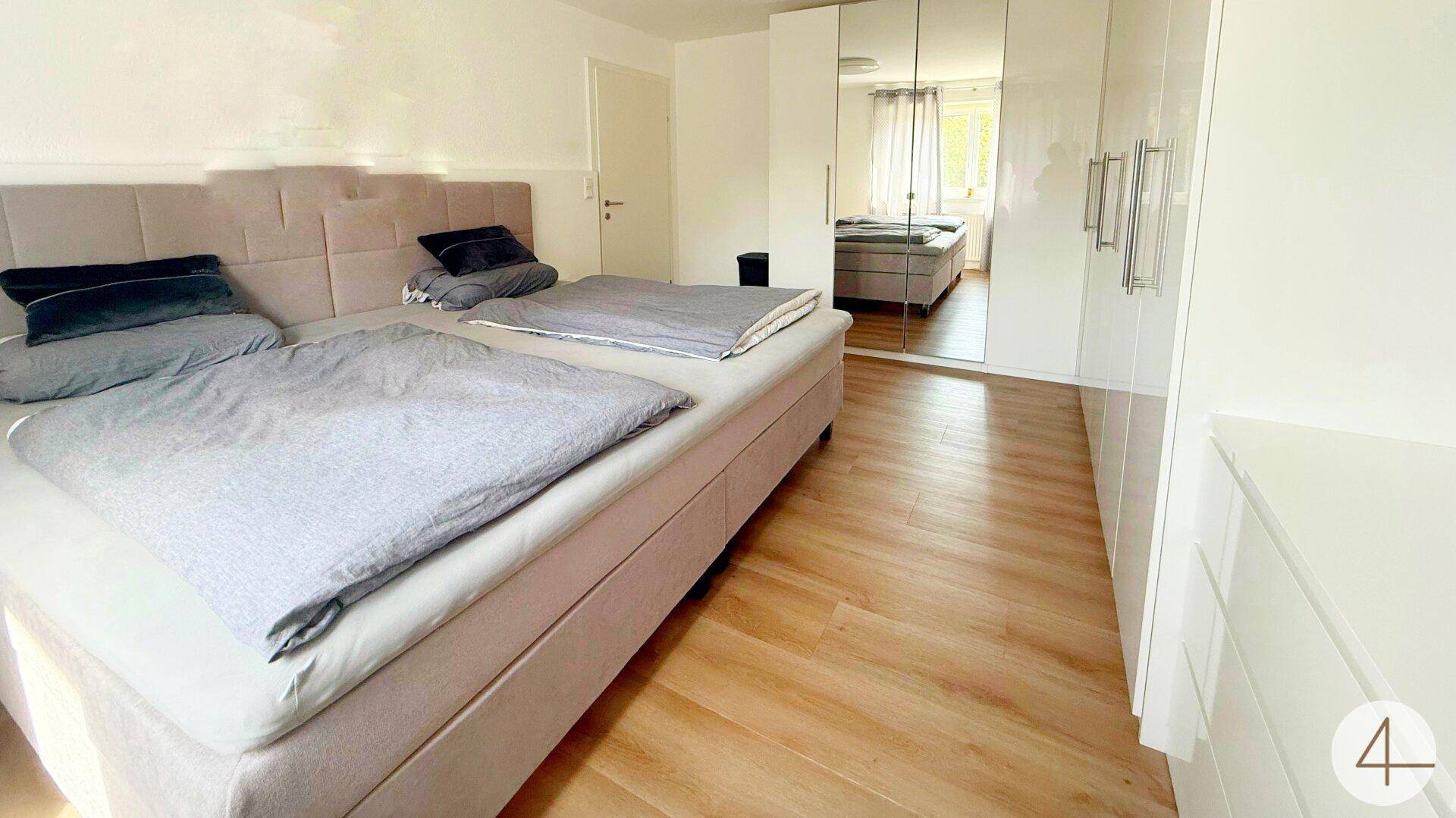 Schlafzimmer mit Doppelbett und einem großen Kleiderschrank mit Spiegeltüren.